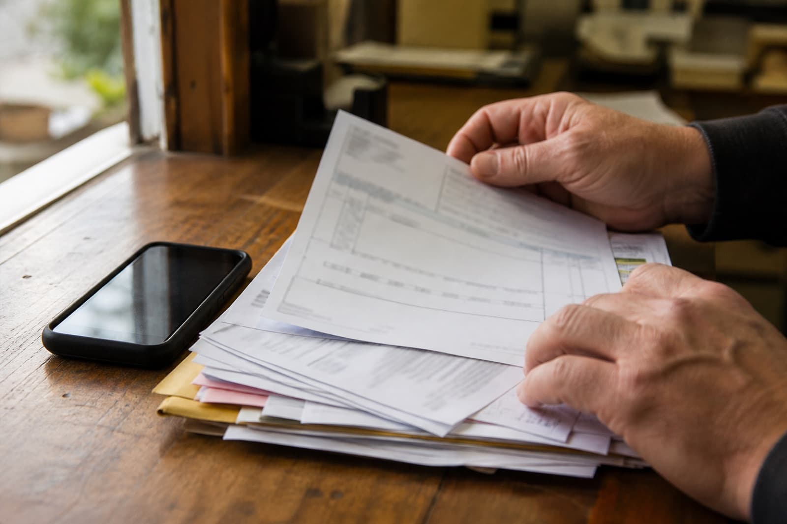 A stack of supplier invoices on a back office desk.