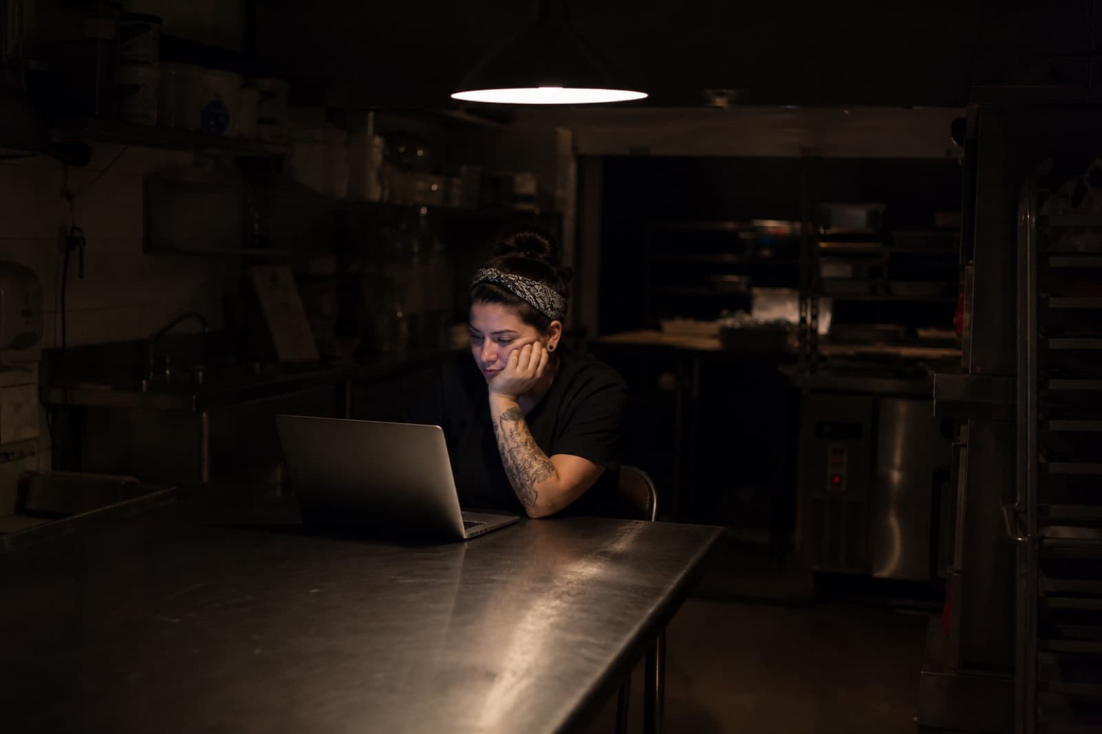 Someone alone at a prep table after close, watching a laptop.