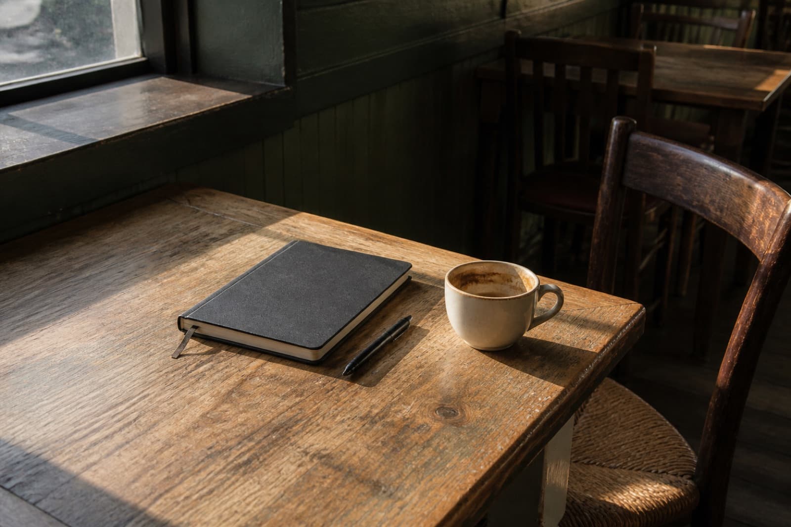 A notebook and a coffee on a corner table in an empty restaurant.
