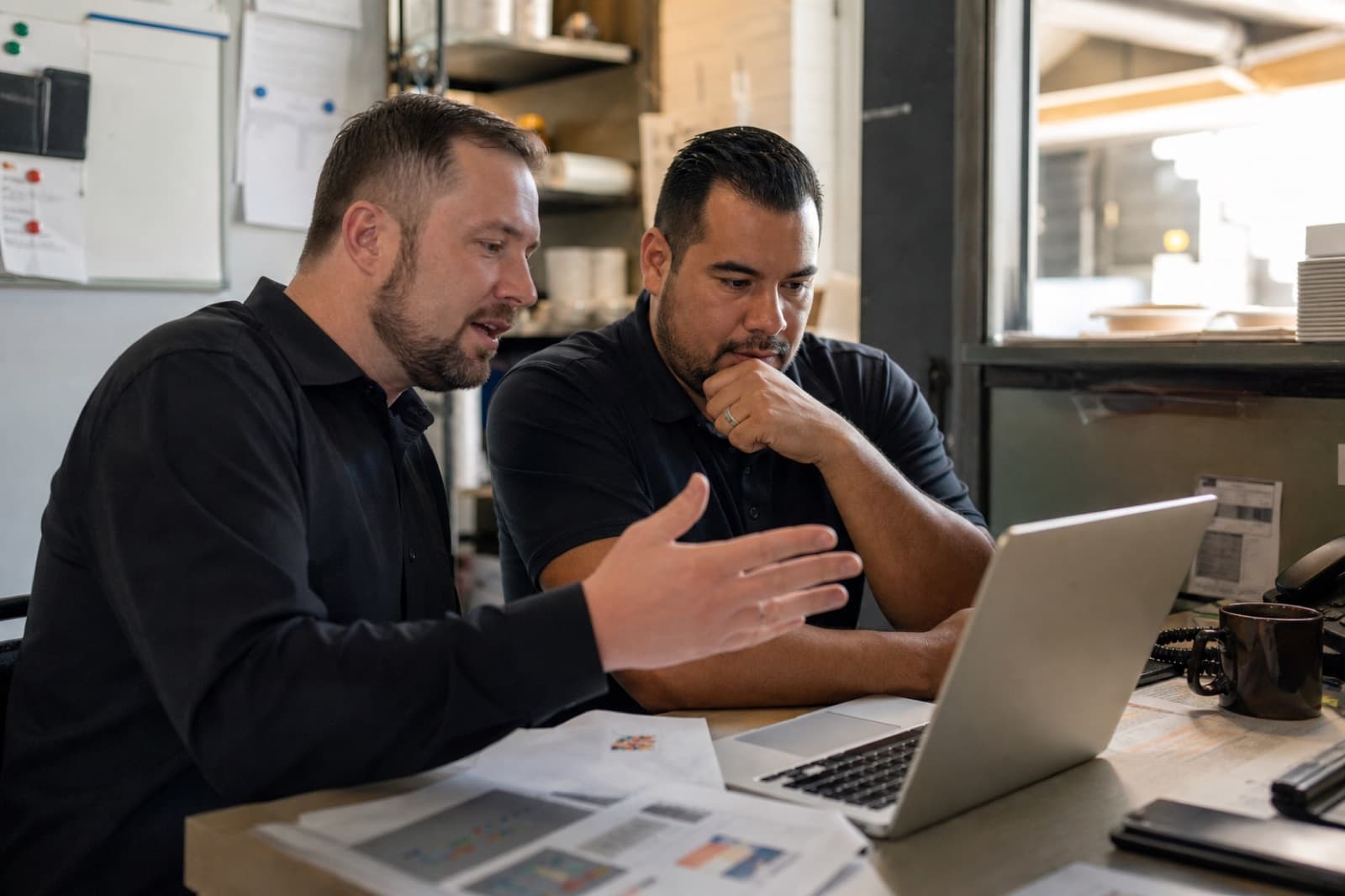Two restaurant managers working through something together on one laptop.